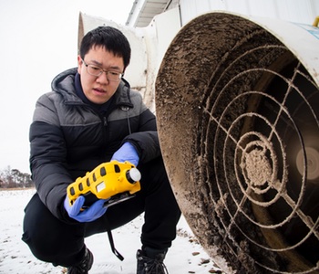 Tian Xia monitors the methane levels coming out of a pig holding pen before setting up a lab-scale non-thermal plasma device at the Barton Farms family pig farm in Homer, MI. Image credit: Robert Coelius/Michigan Engineering